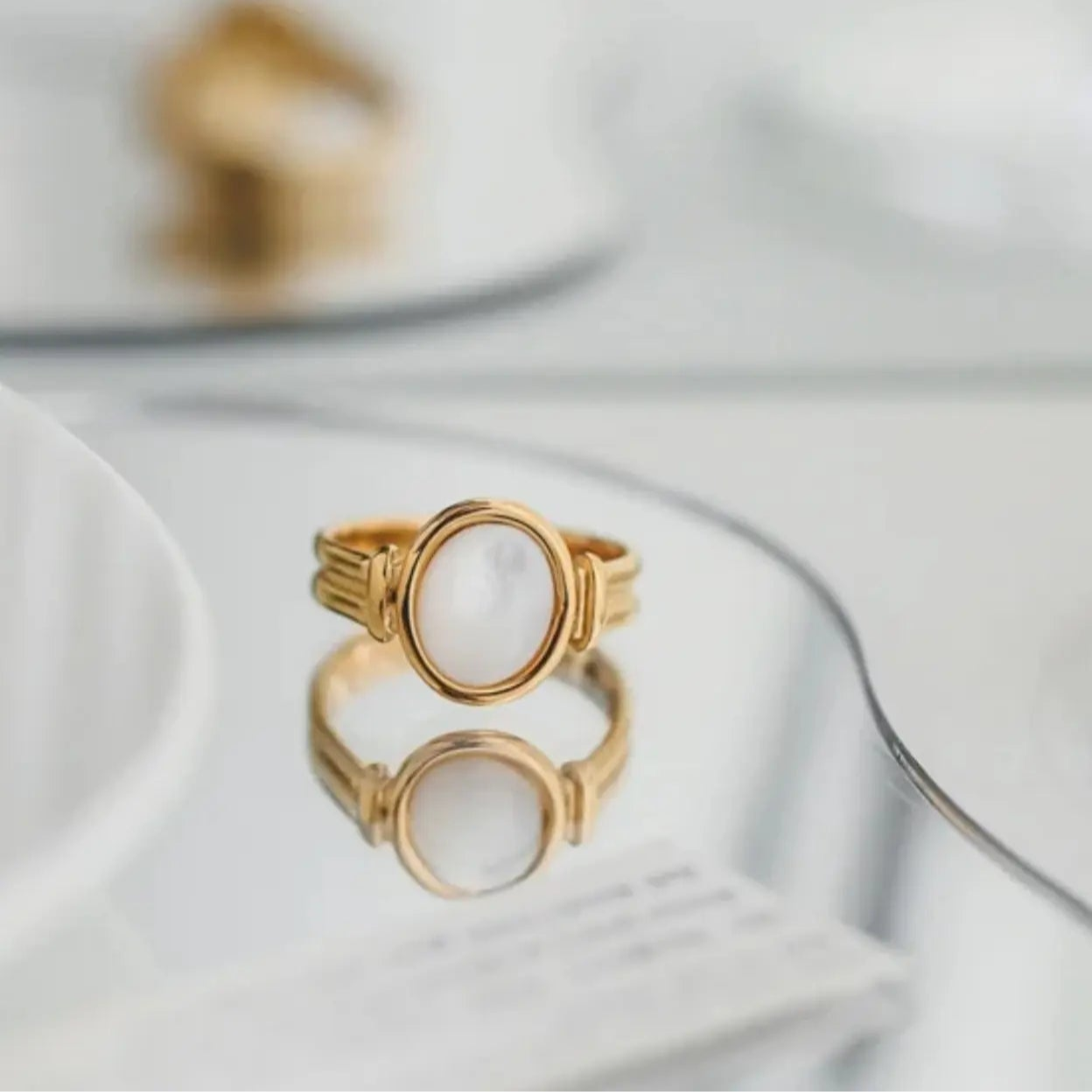 Gold ring with a circular design on a reflective surface